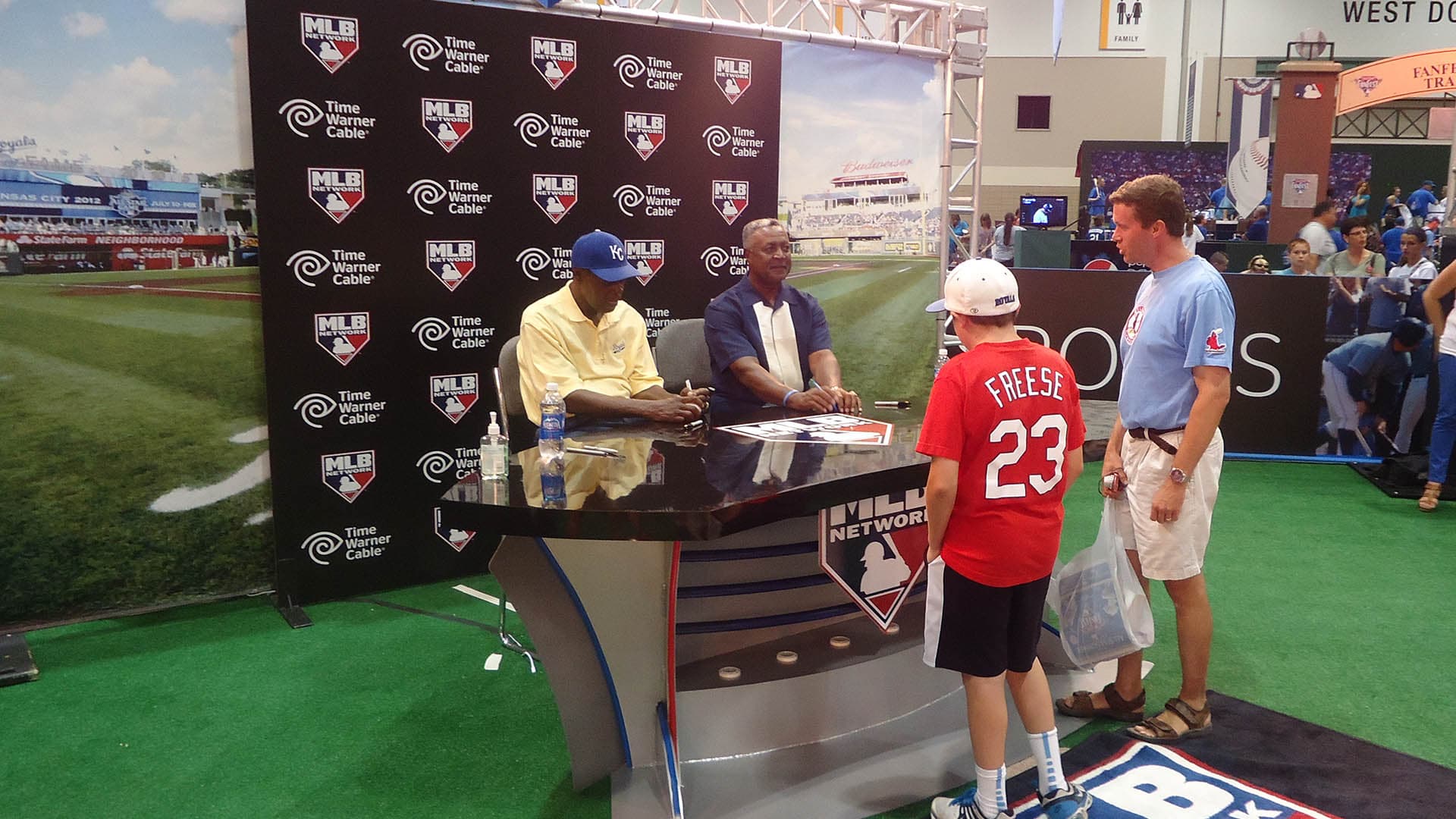 People sitting behind a broadcast booth at a trade show