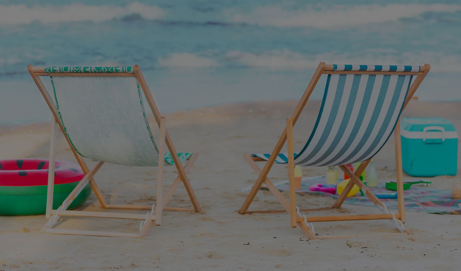 2 beach chairs sit out on the sand in front of the water