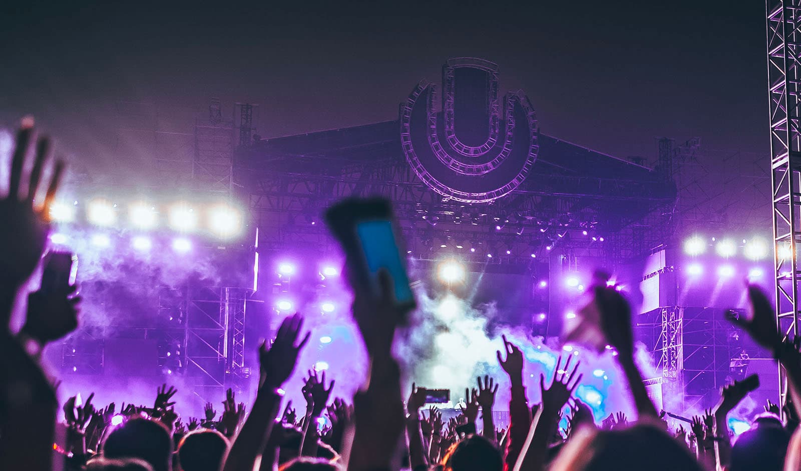 Hands up in a crowd watching a concert at a music festival