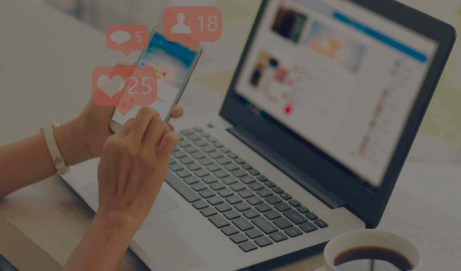 A laptop and an iPhone. Hearts representing social likes float around.